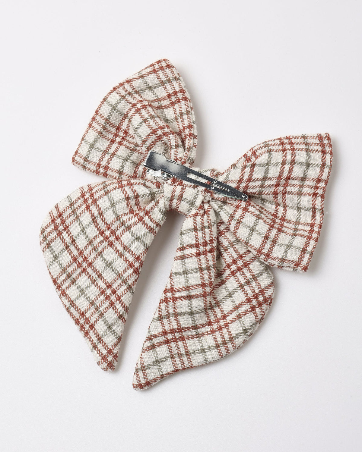 A children's hair bow featuring a red, white, and brown plaid pattern with a metal alligator clip attached to the back.