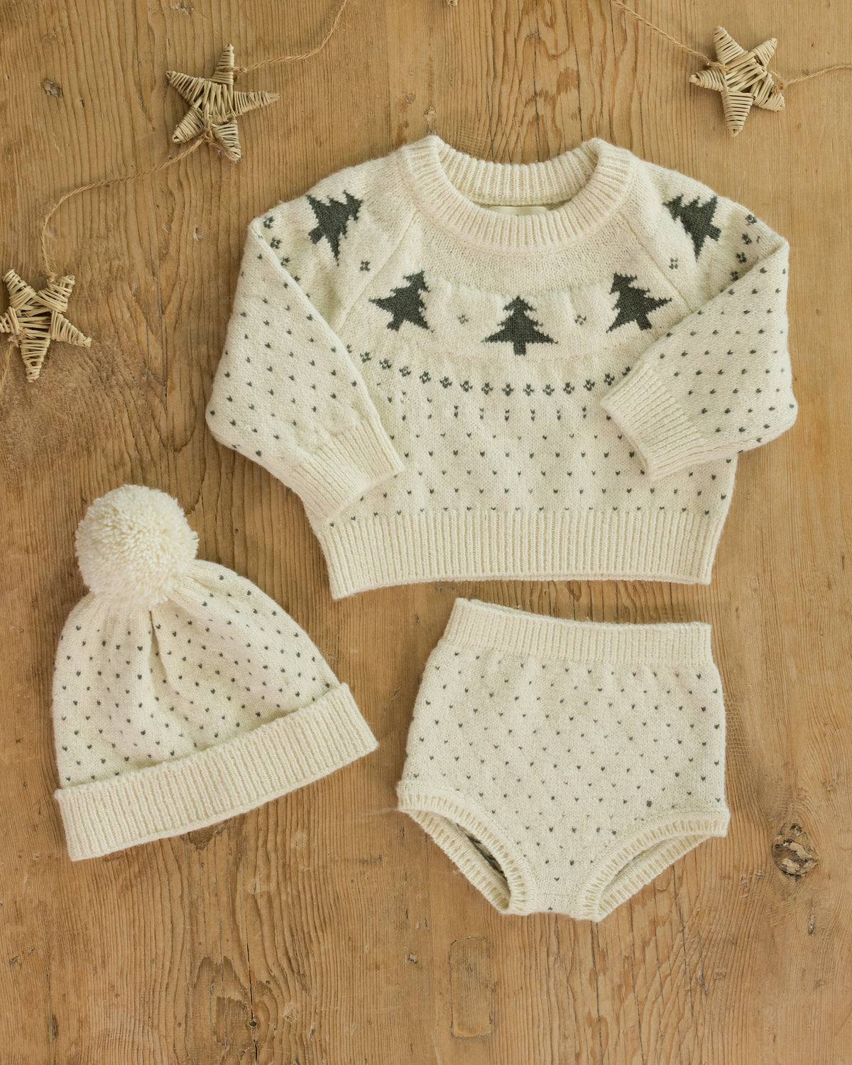 Knitted baby set with sweater, hat, and shorts on a wooden surface