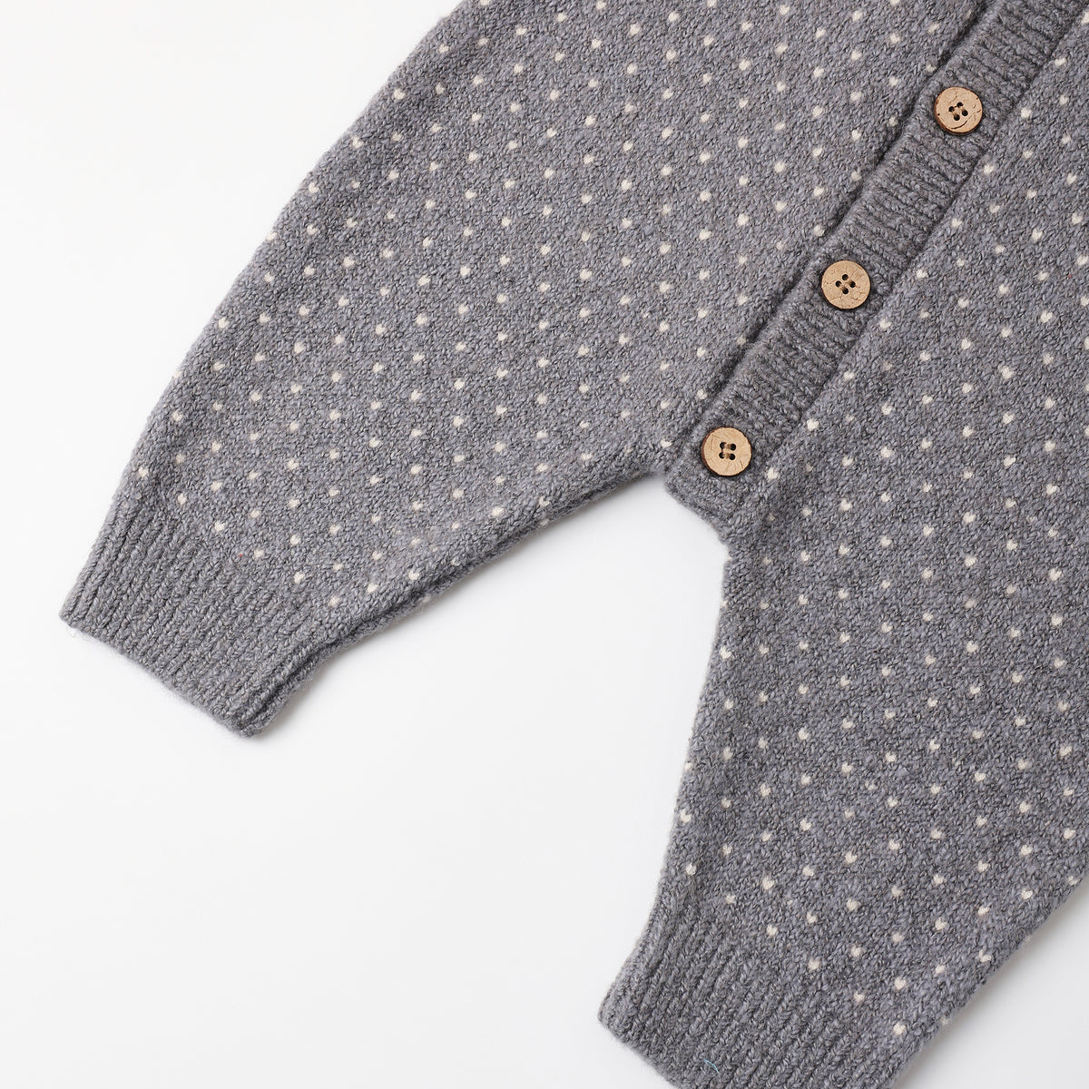 The image shows a light blue or slate-colored knitted baby onesie or romper with a textured dot pattern front button closure.