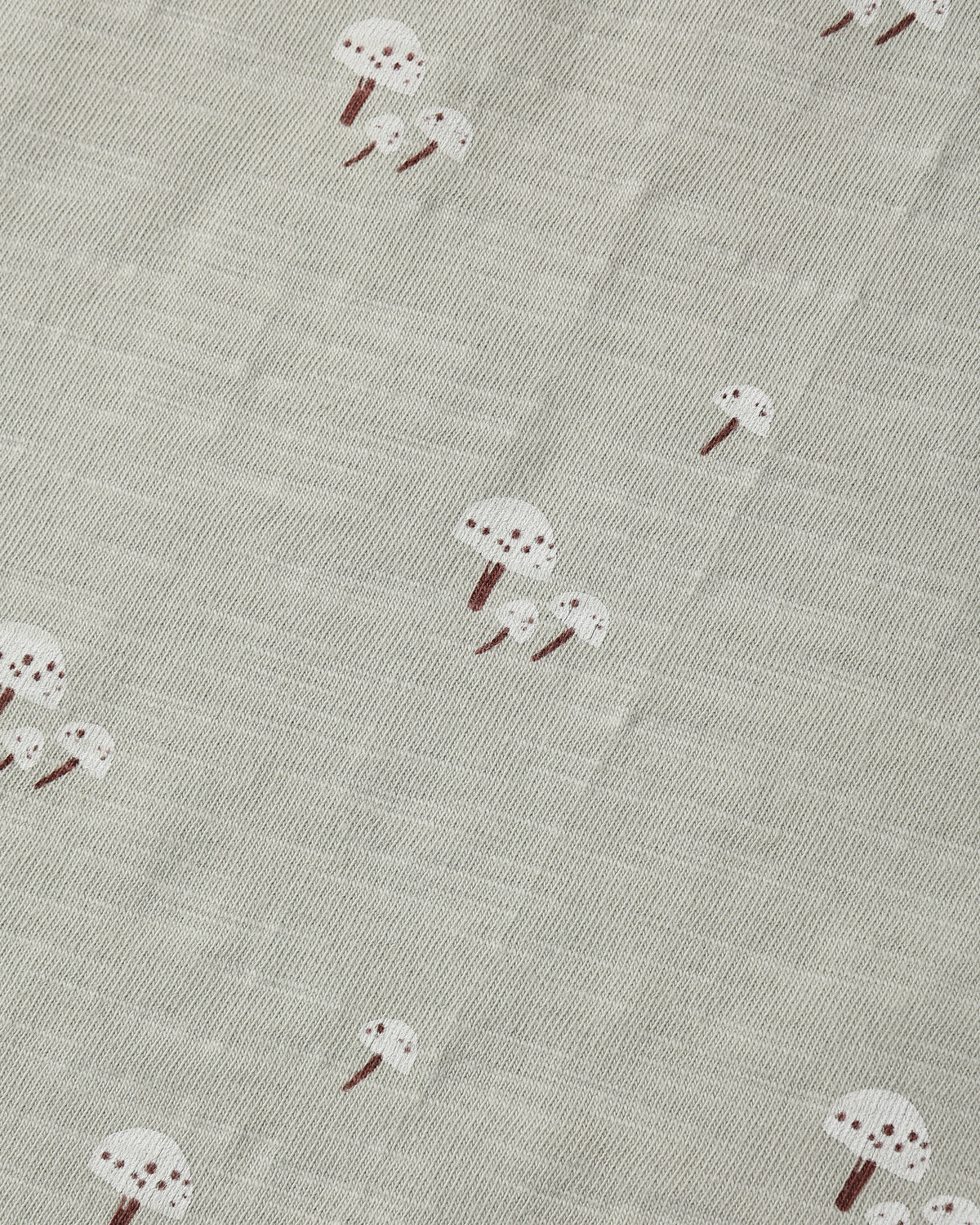 A close-up of a textured fabric featuring a repeating pattern of small white mushrooms with brown stems on a light gray-beige background.