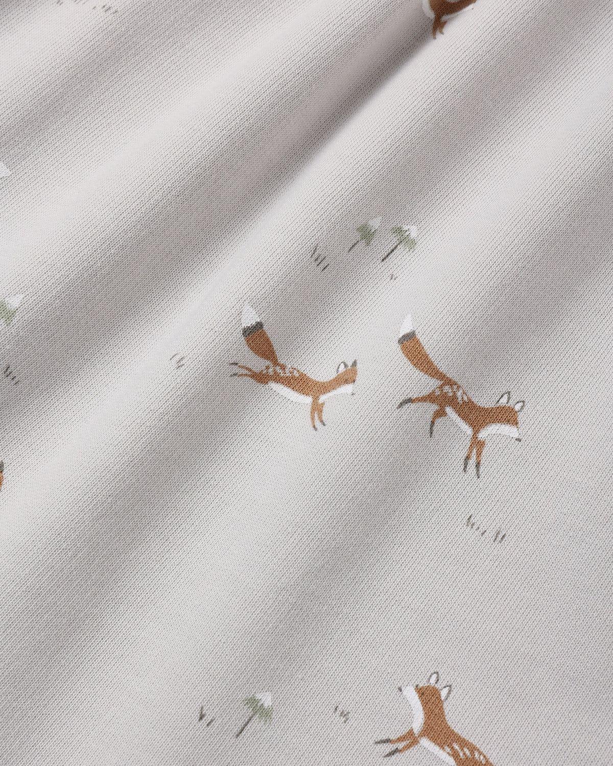 Close-up of a light cream fabric with a repeating print of brown foxes and small white flowers.