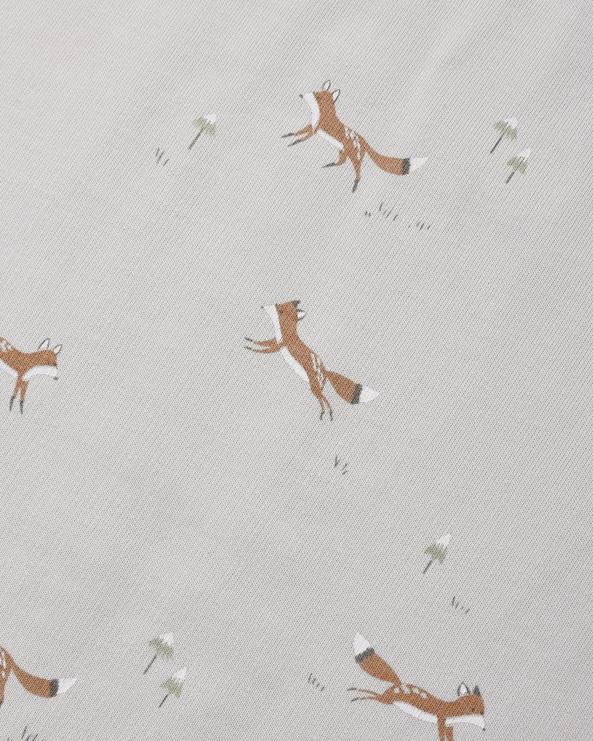 A close-up of a light beige fabric with a repeating pattern of brown foxes and small white flowers.