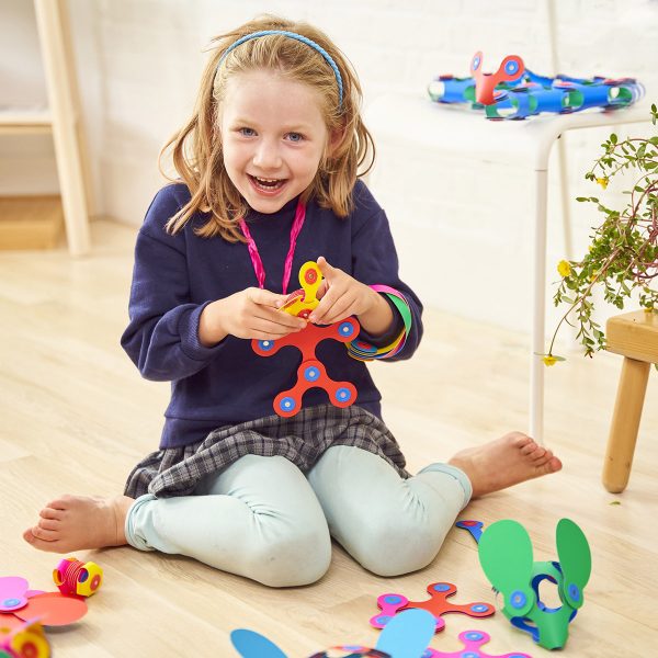 A young girl colorful Clixo magnetic play set with packaging on a biege background