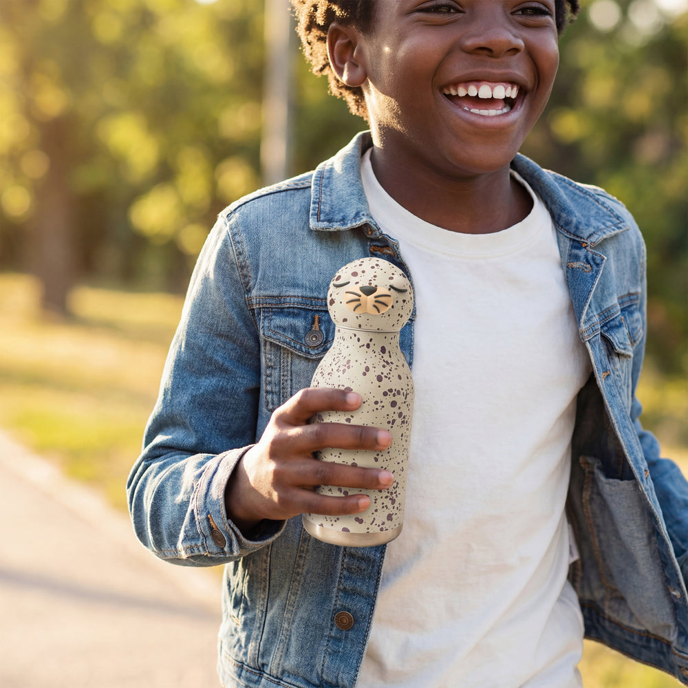 Child holding a small figurine outdoors with a blurred natural background