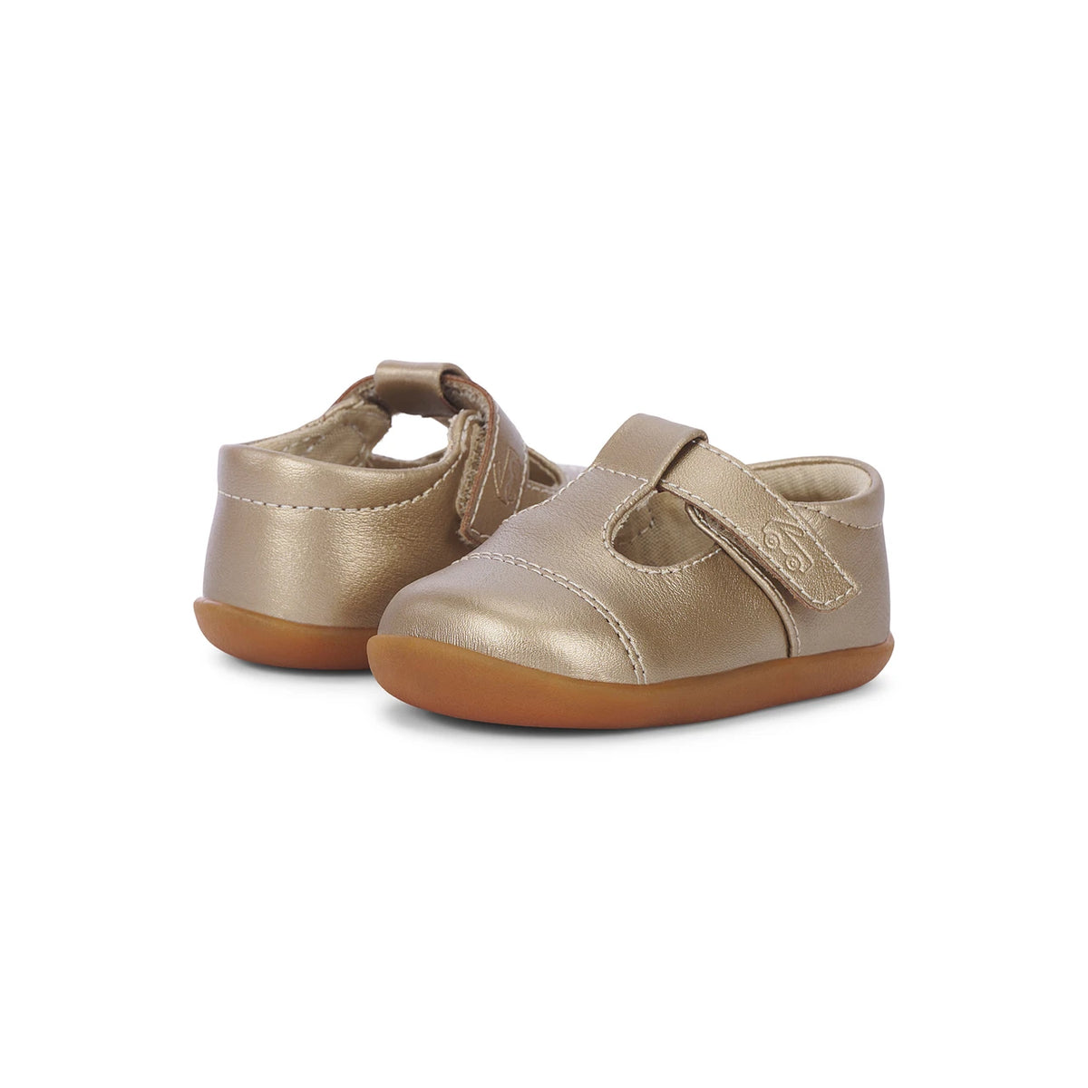 Pair of gold baby shoes with brown soles on a white background