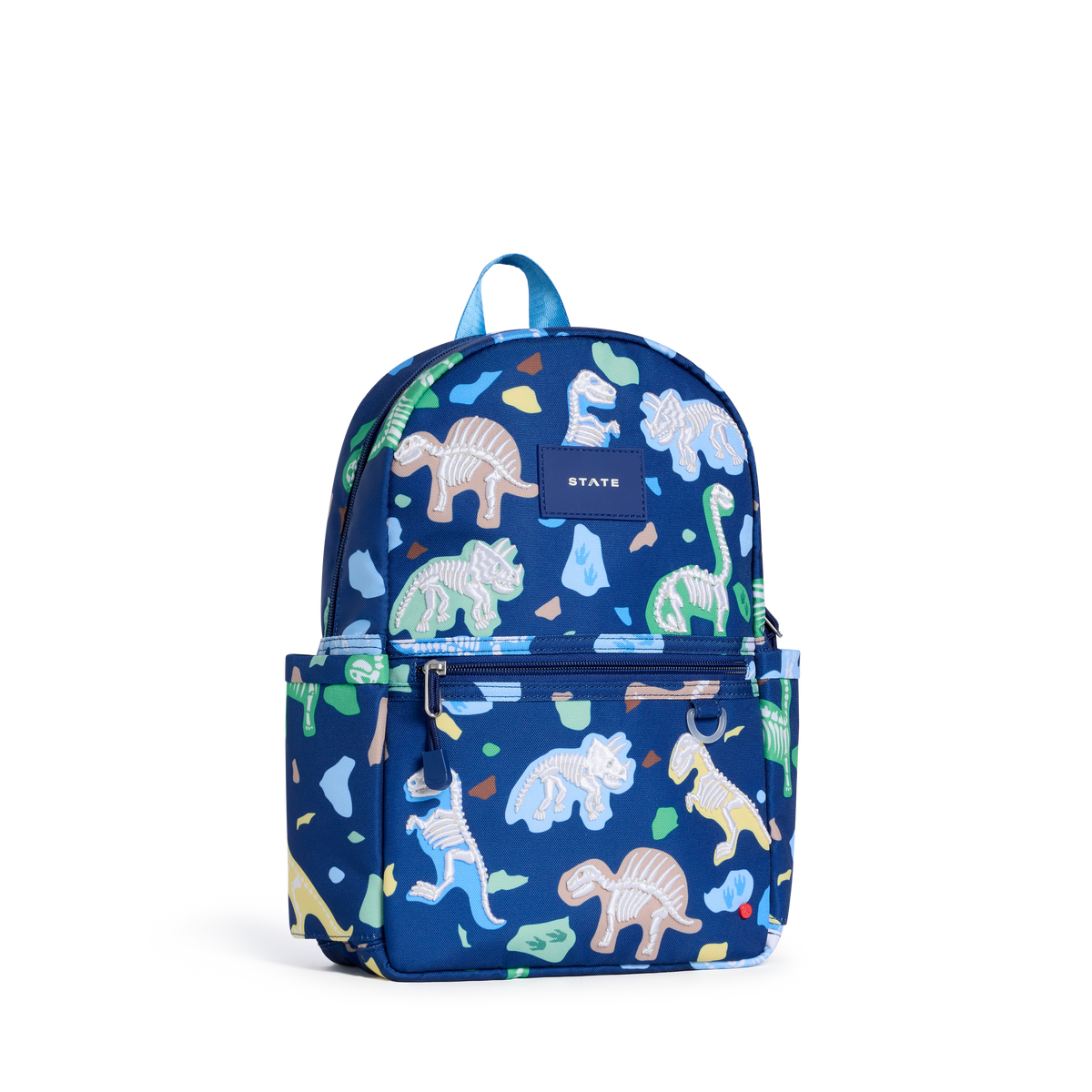 A blue backpack with a colorful dinosaur and rock print, featuring a top handle, front zippered pocket, and a small 'STATE' brand patch on the upper front.