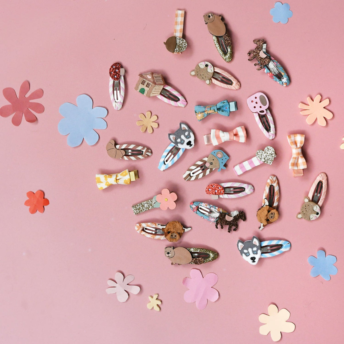 Collection of various hair clips on a pink background with decorative flowers.