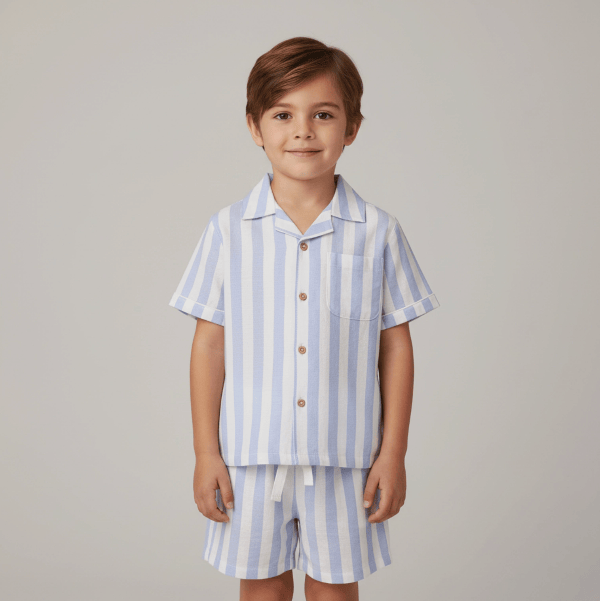 Child wearing a blue and white striped shirt and shorts set on a plain background