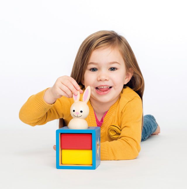 Child playing with a colorful toy box and rabbit figurine on a white background