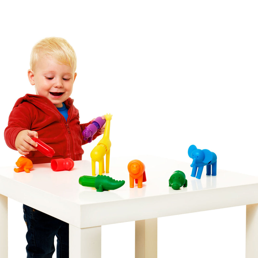 Child playing with colorful toy animals on a white table
