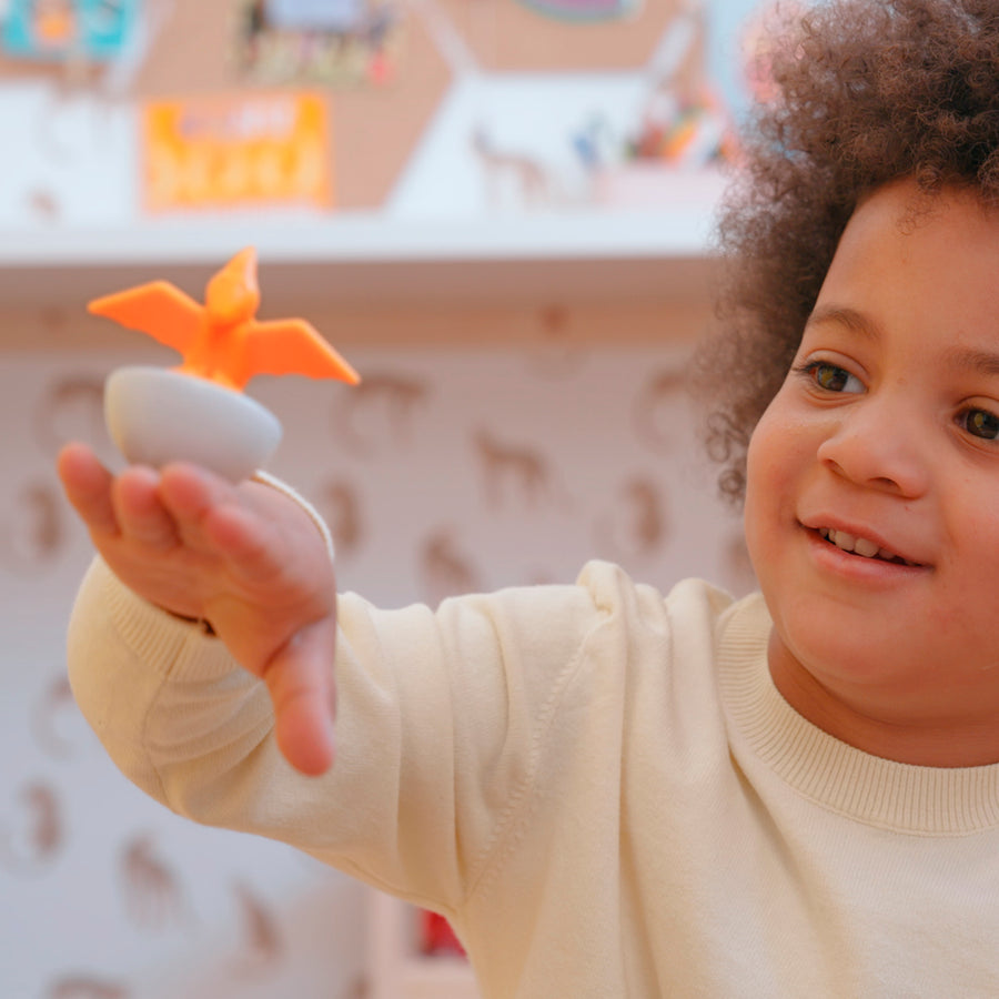 Child holding an orange toy in a playroom setting