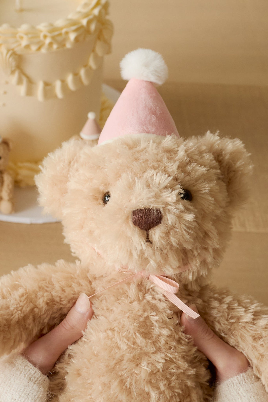 Teddy bear wearing a pink party hat with a blurred background