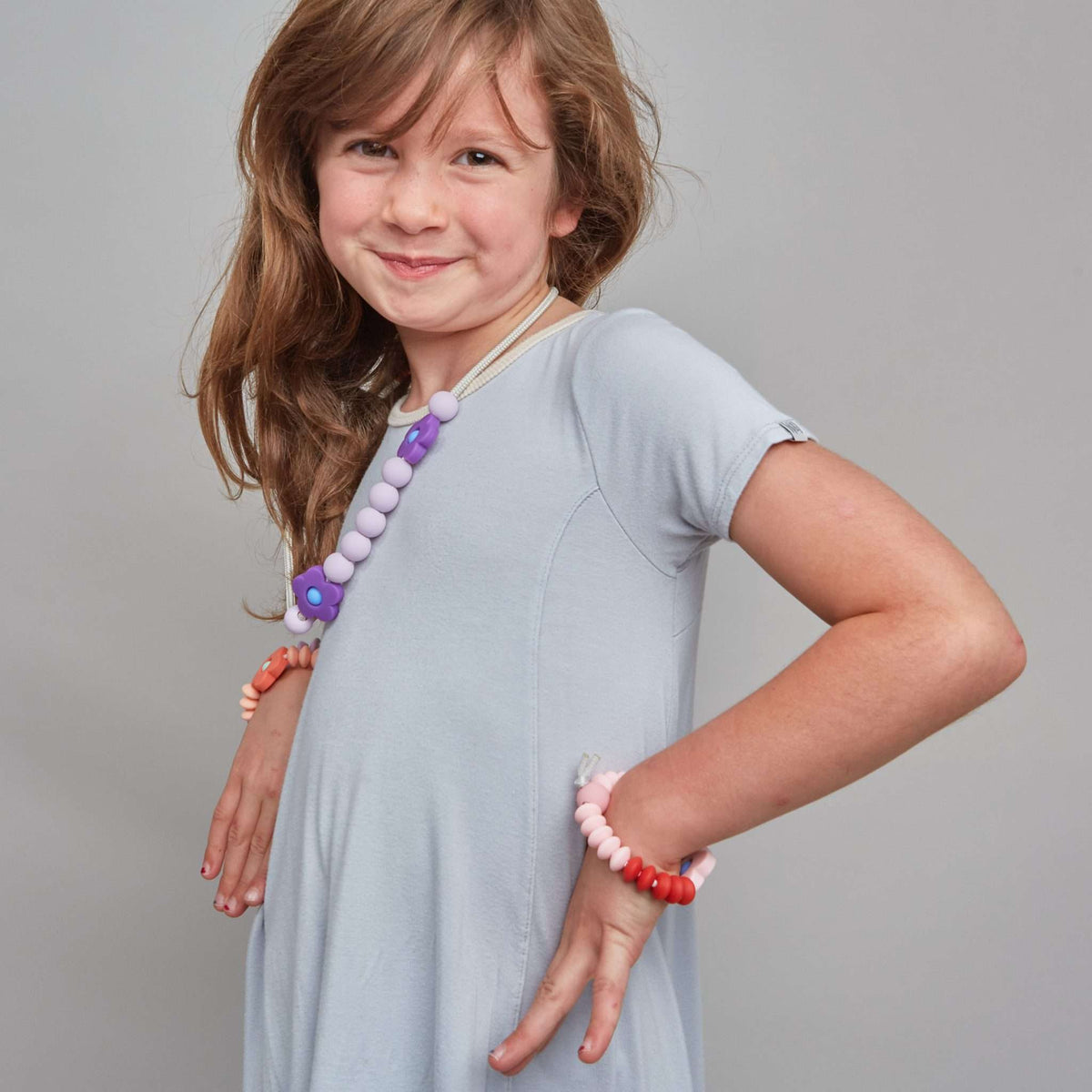 Young girl wearing colorful bracelets on a plain background