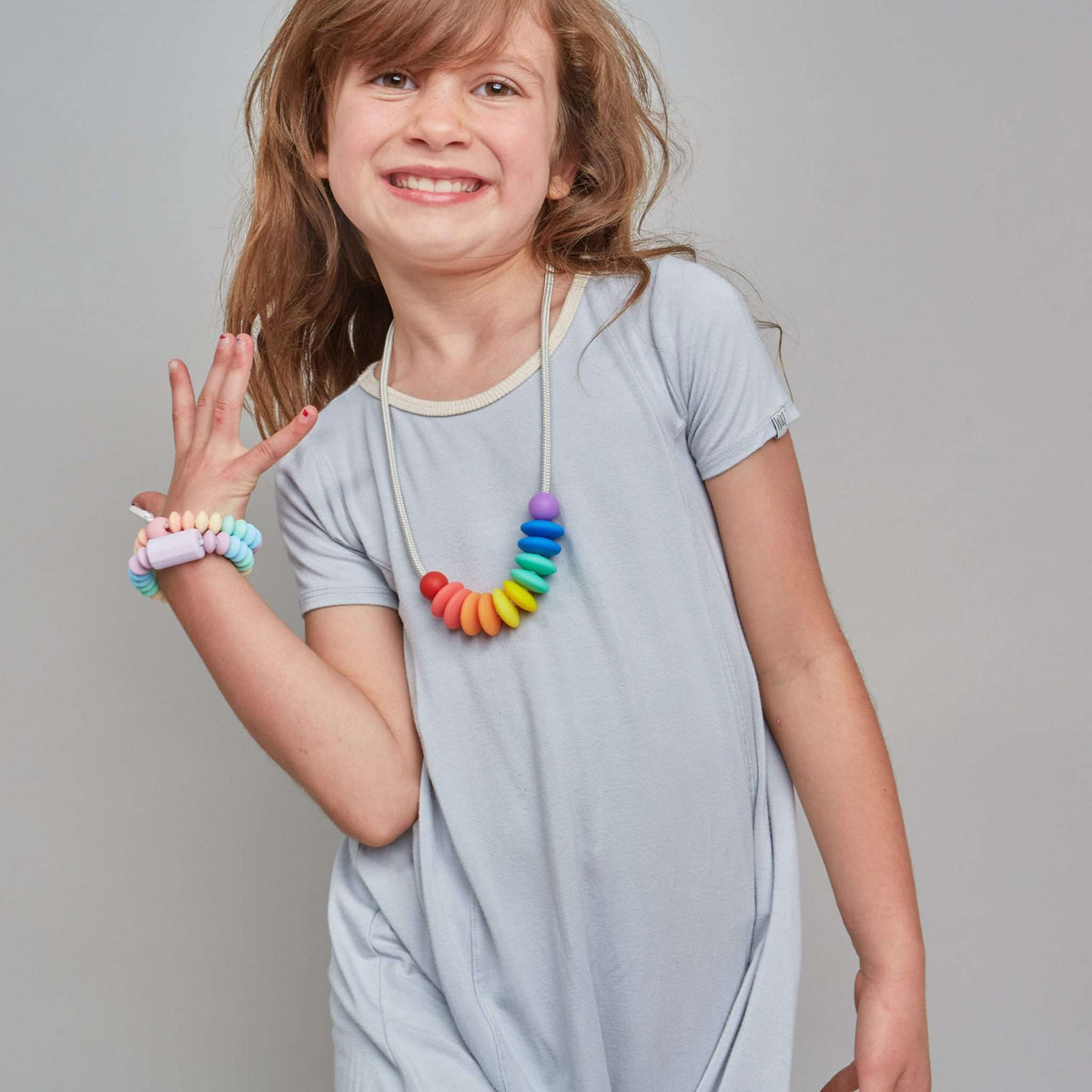 Child wearing a colorful necklace and bracelets on a plain background