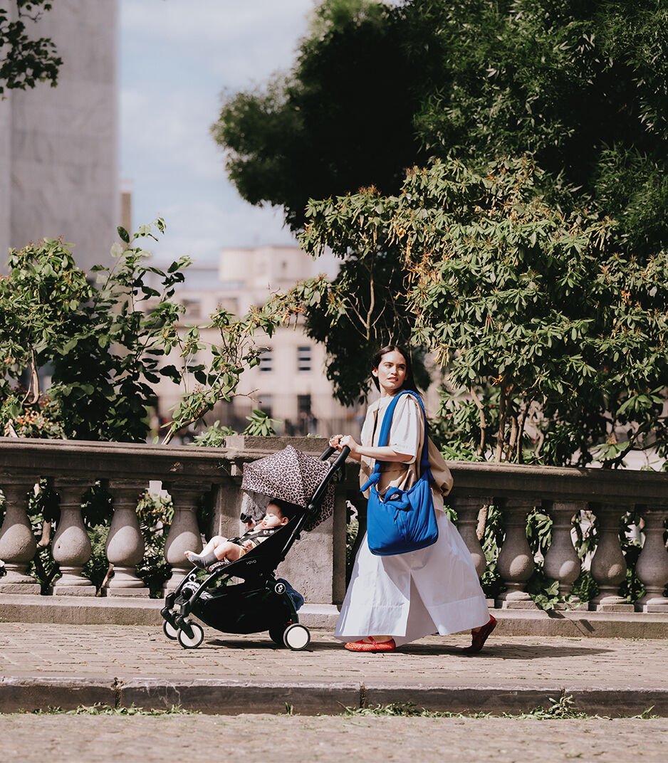 Woman pushing a stroller with a child in an urban park setting