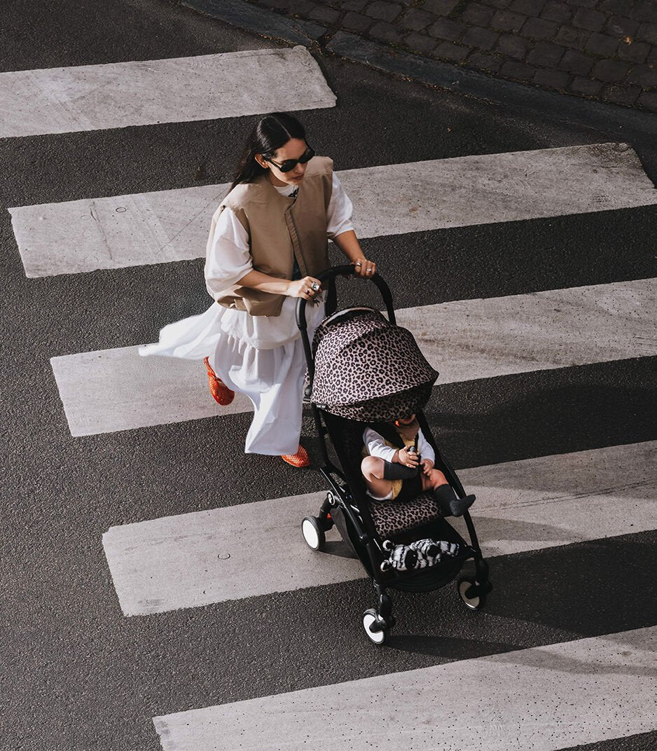 Woman pushing a stroller with a child on a crosswalk