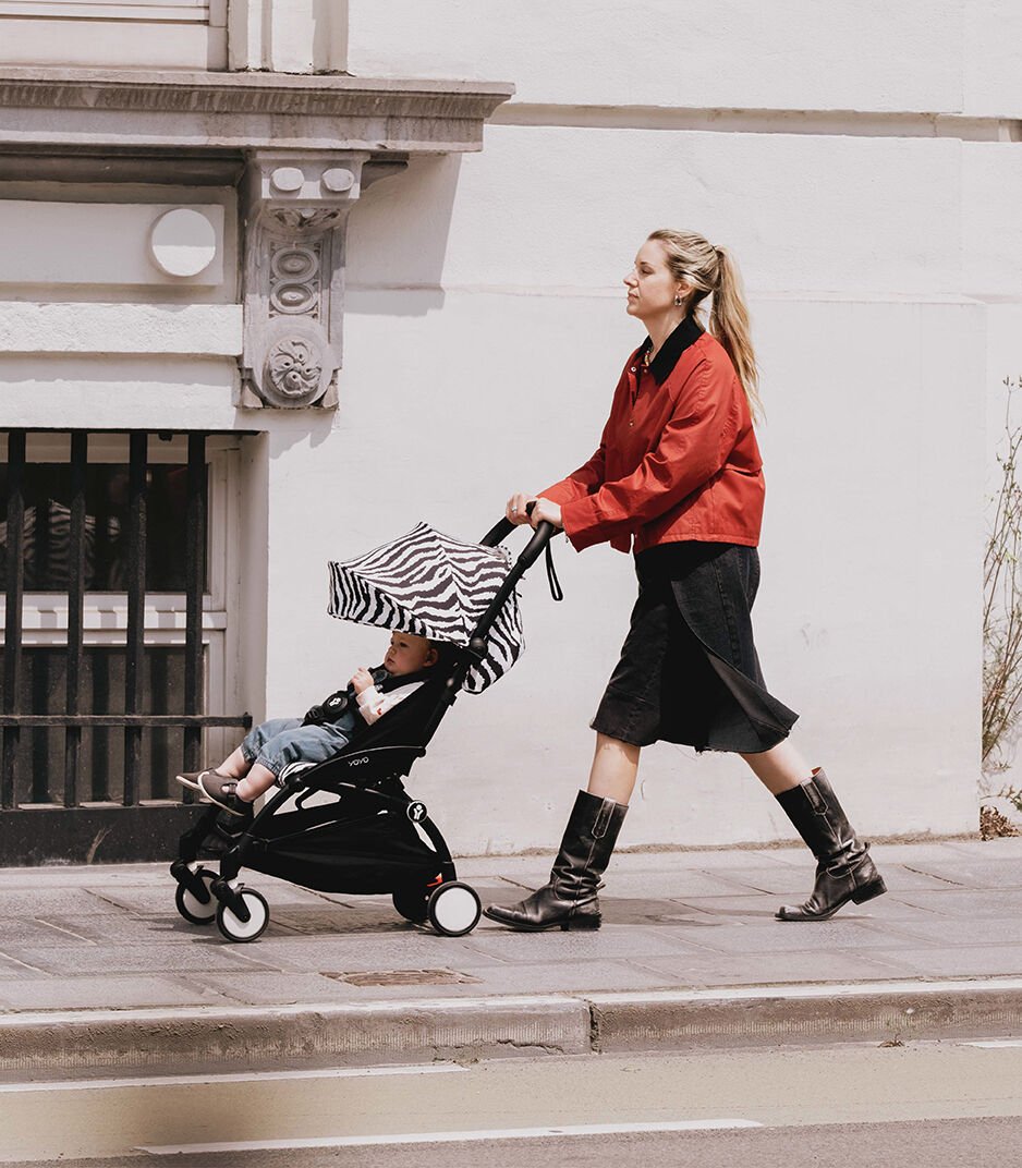 Woman pushing a stroller with a child on a city street.