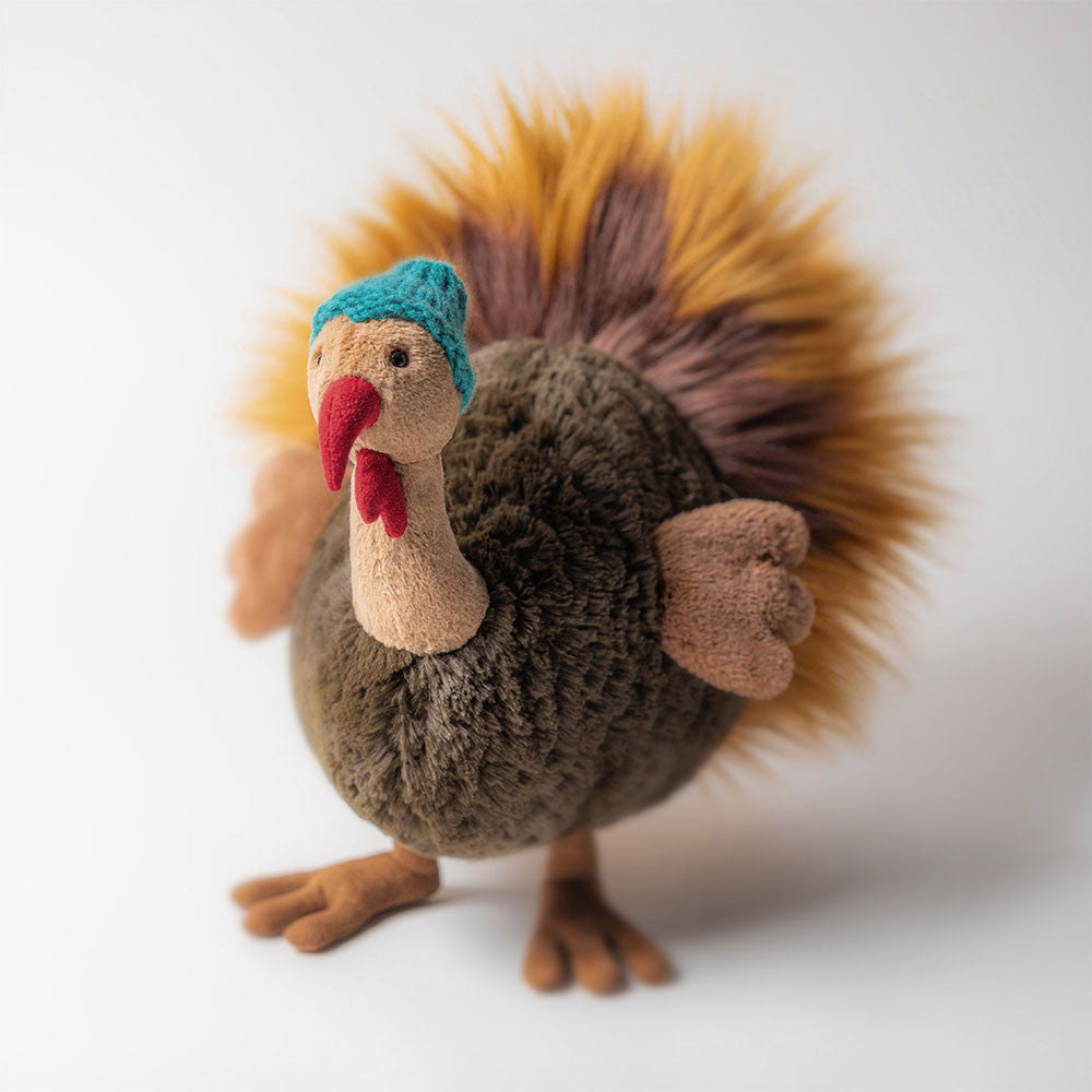 Plush toy turkey with a blue hat on a white background