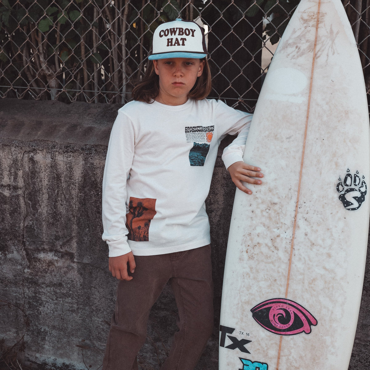 Person holding a surfboard with a chain-link fence in the background