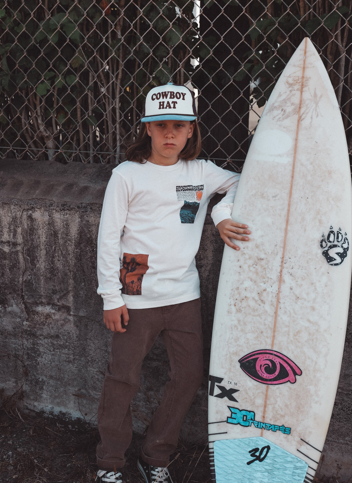 Person holding a surfboard with a chain-link fence in the background
