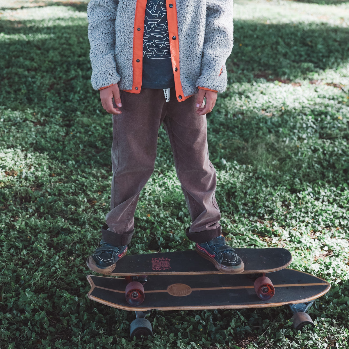 Person standing on a skateboard in a grassy area