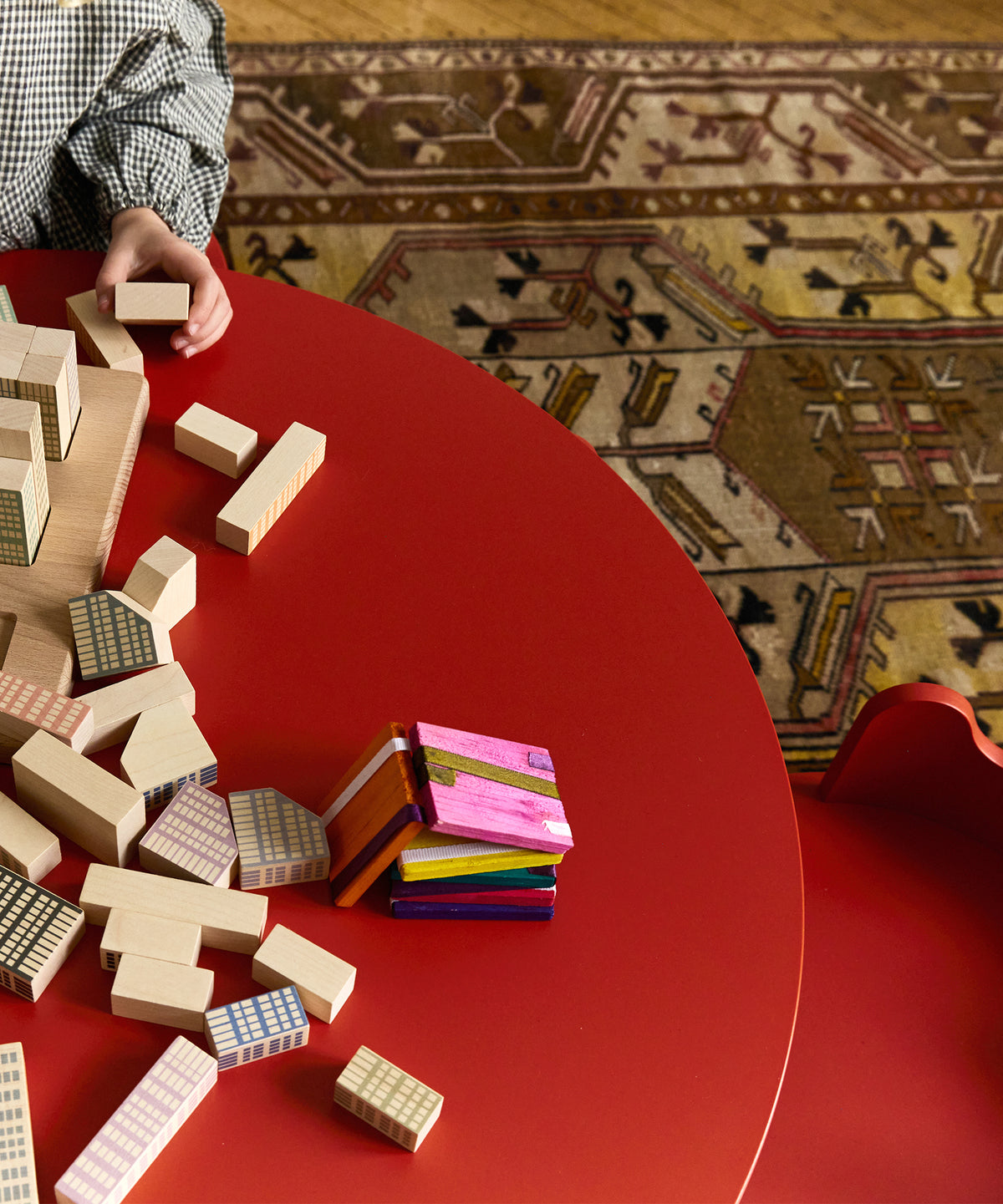 Colorful building blocks on a red table with a patterned rug in the background