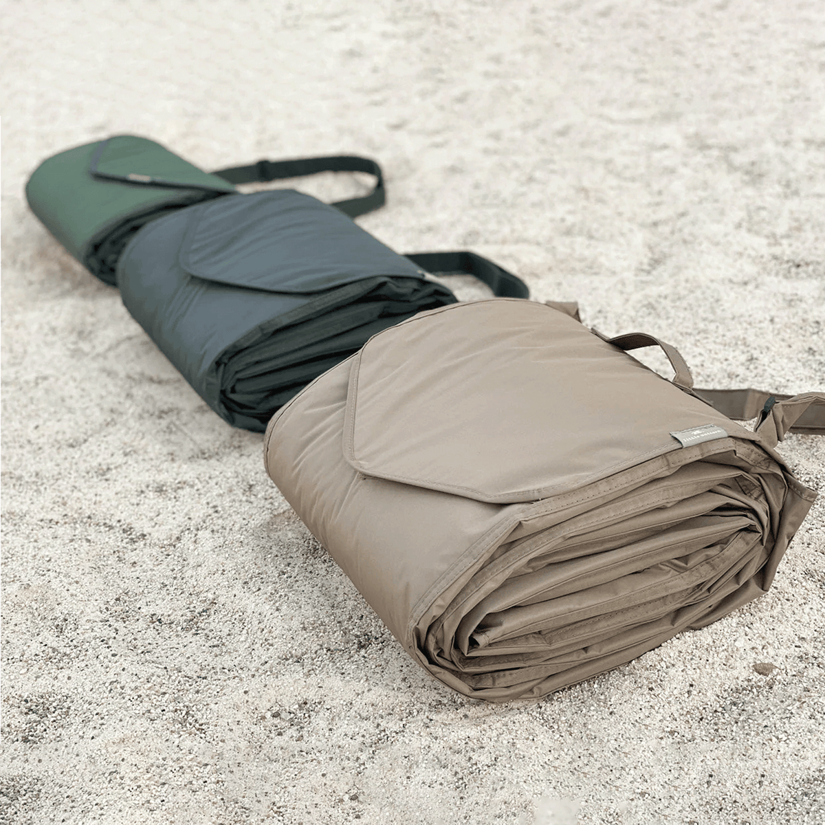 Folded camping mat and green sleeping pad on sandy ground