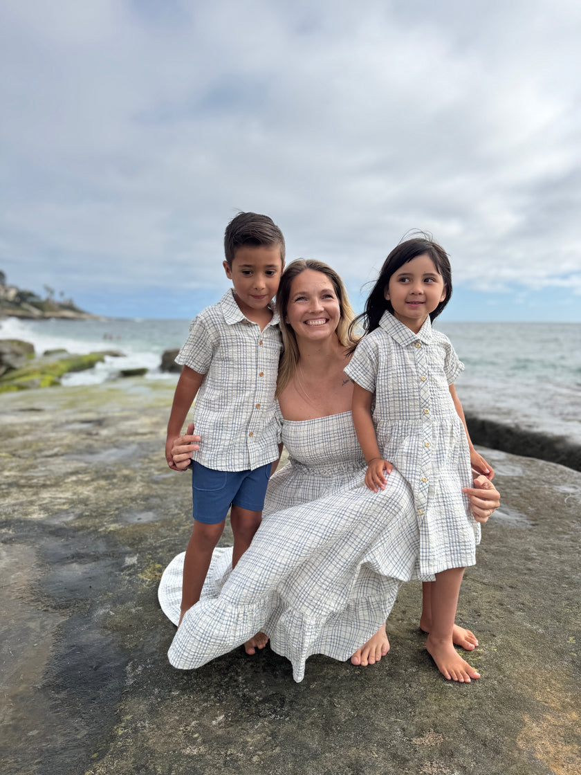 Woman with two children on a rocky beach with ocean and sky in the background
