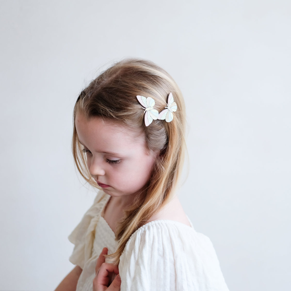 Young girl with butterfly hair clips on a plain background