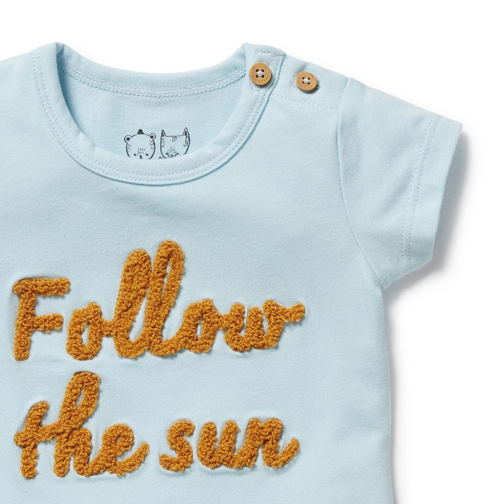 Light blue baby onesie with 'Follow the sun' text in orange on a white background