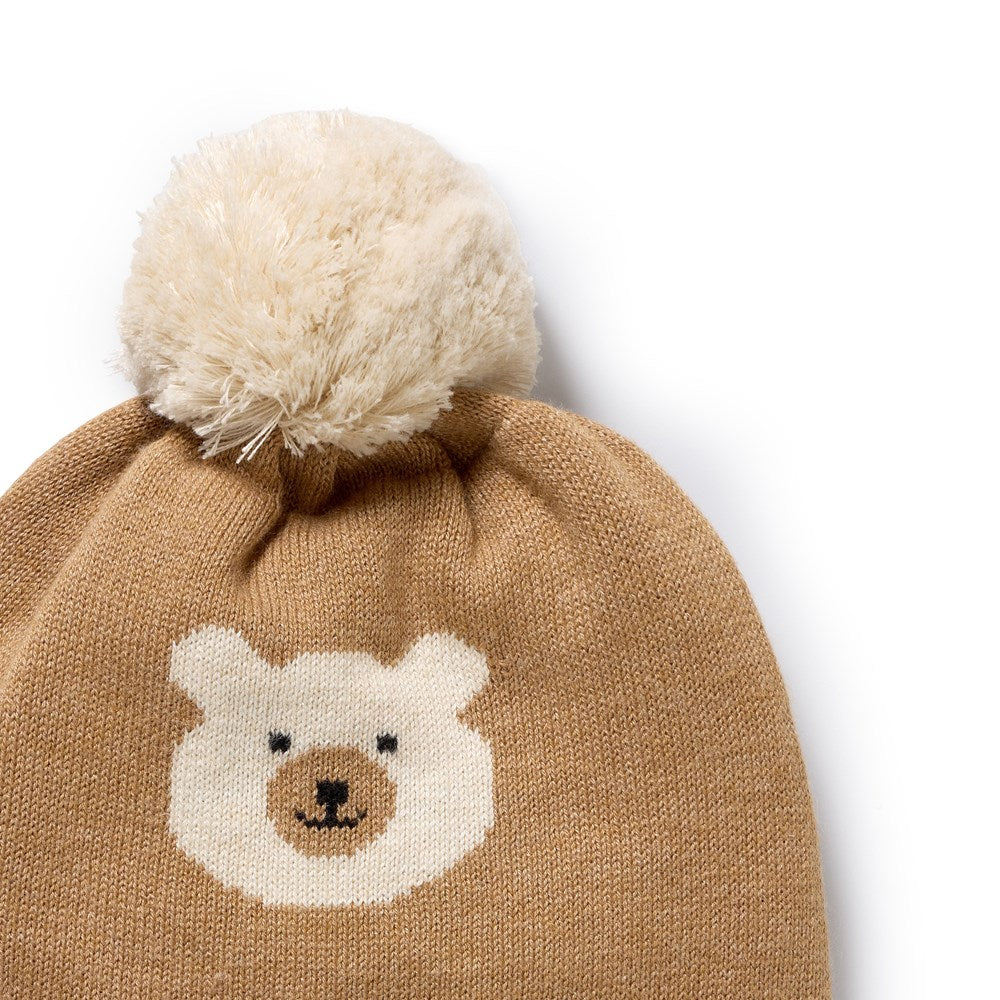 Brown knit hat with bear face design and white pom-pom on a white background
