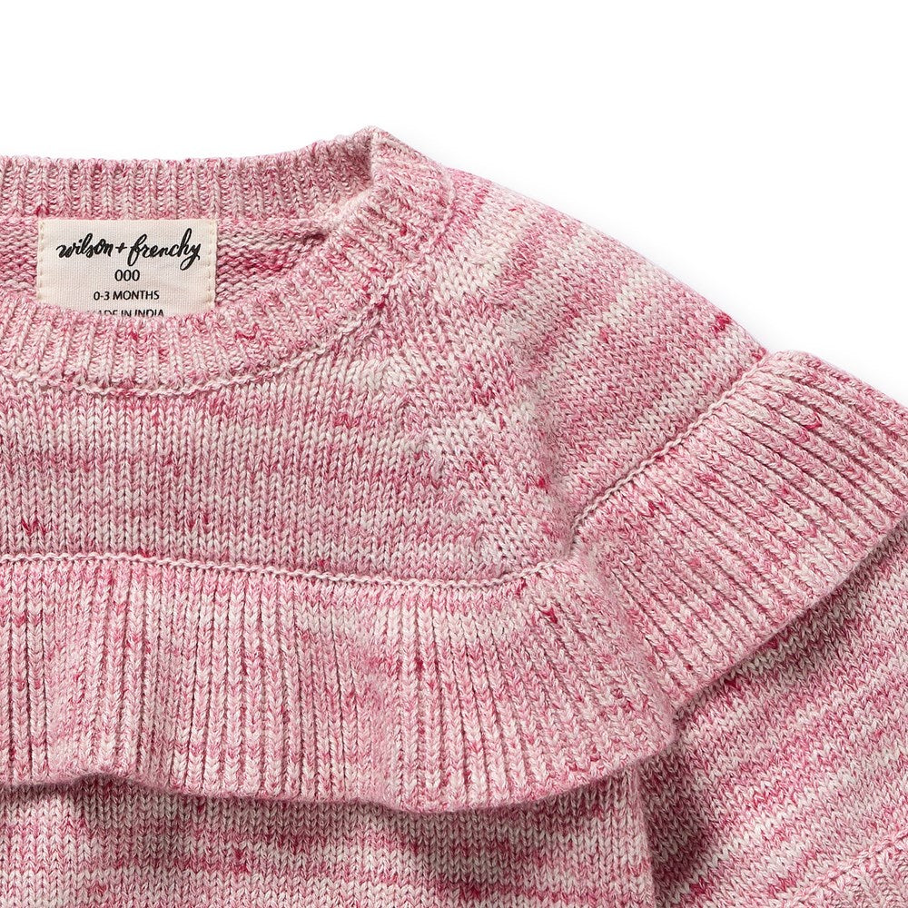 Close-up of a pink knitted garment with a brand label on a white background