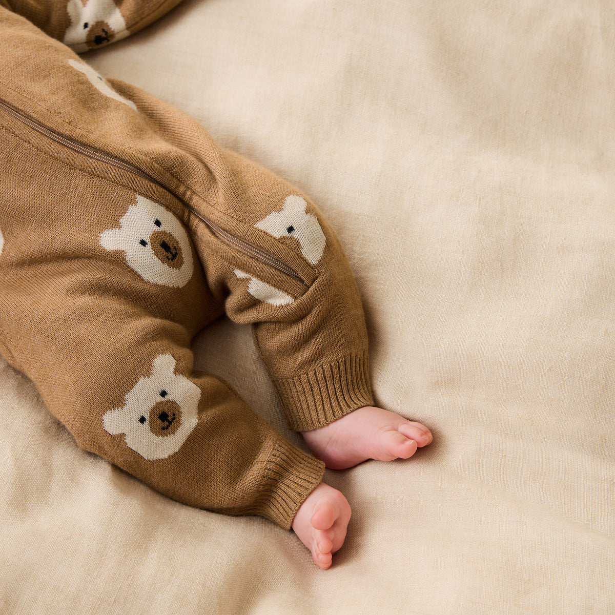 Brown baby romper with bear designs on a beige blanket