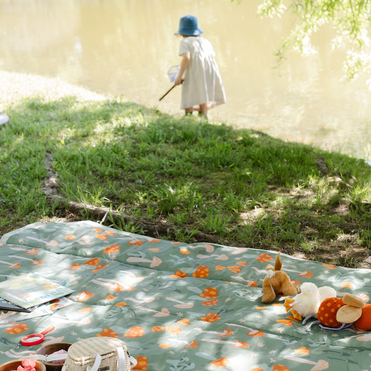 Child playing with toys on a patterned blanket outdoors