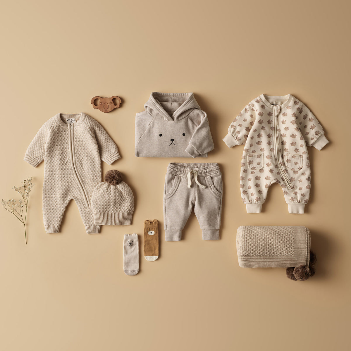 Collection of baby clothing and accessories on a beige background