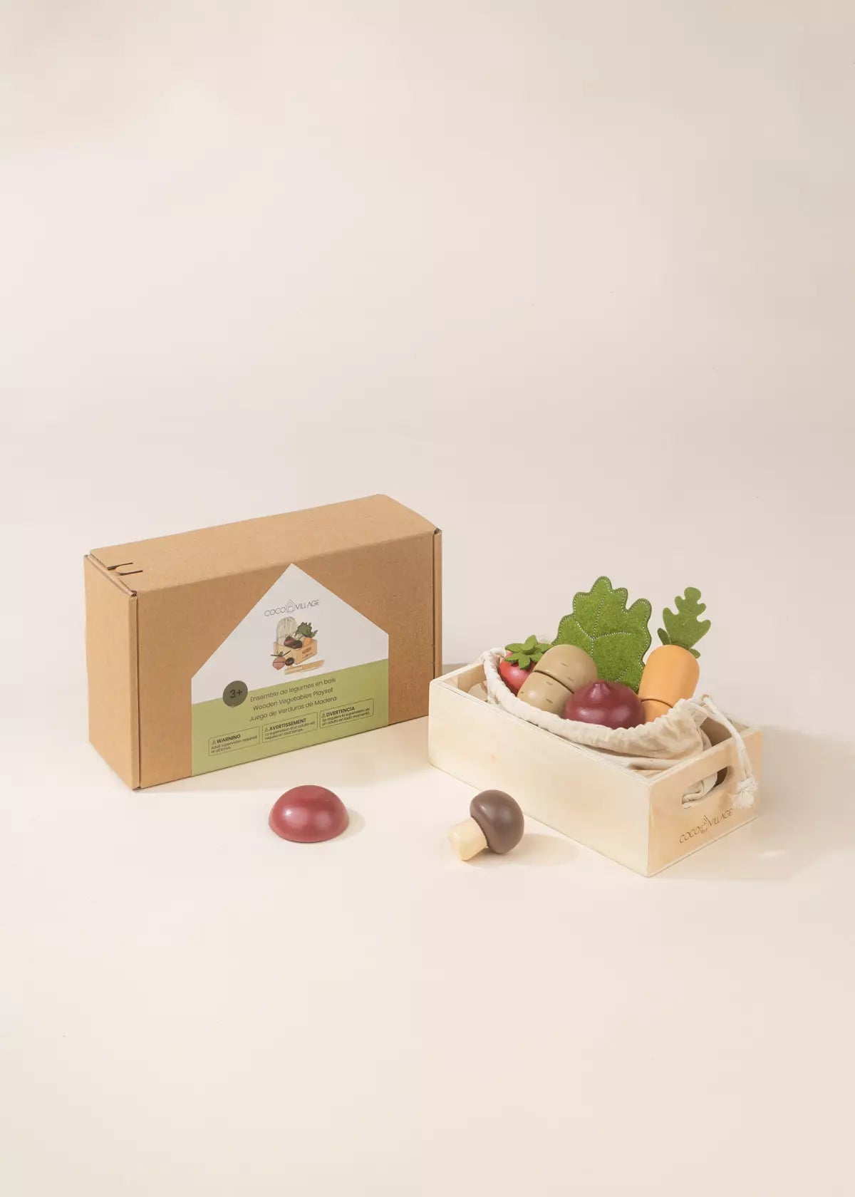 Cardboard box with a green label, wooden fruits and vegetables on a white surface.
