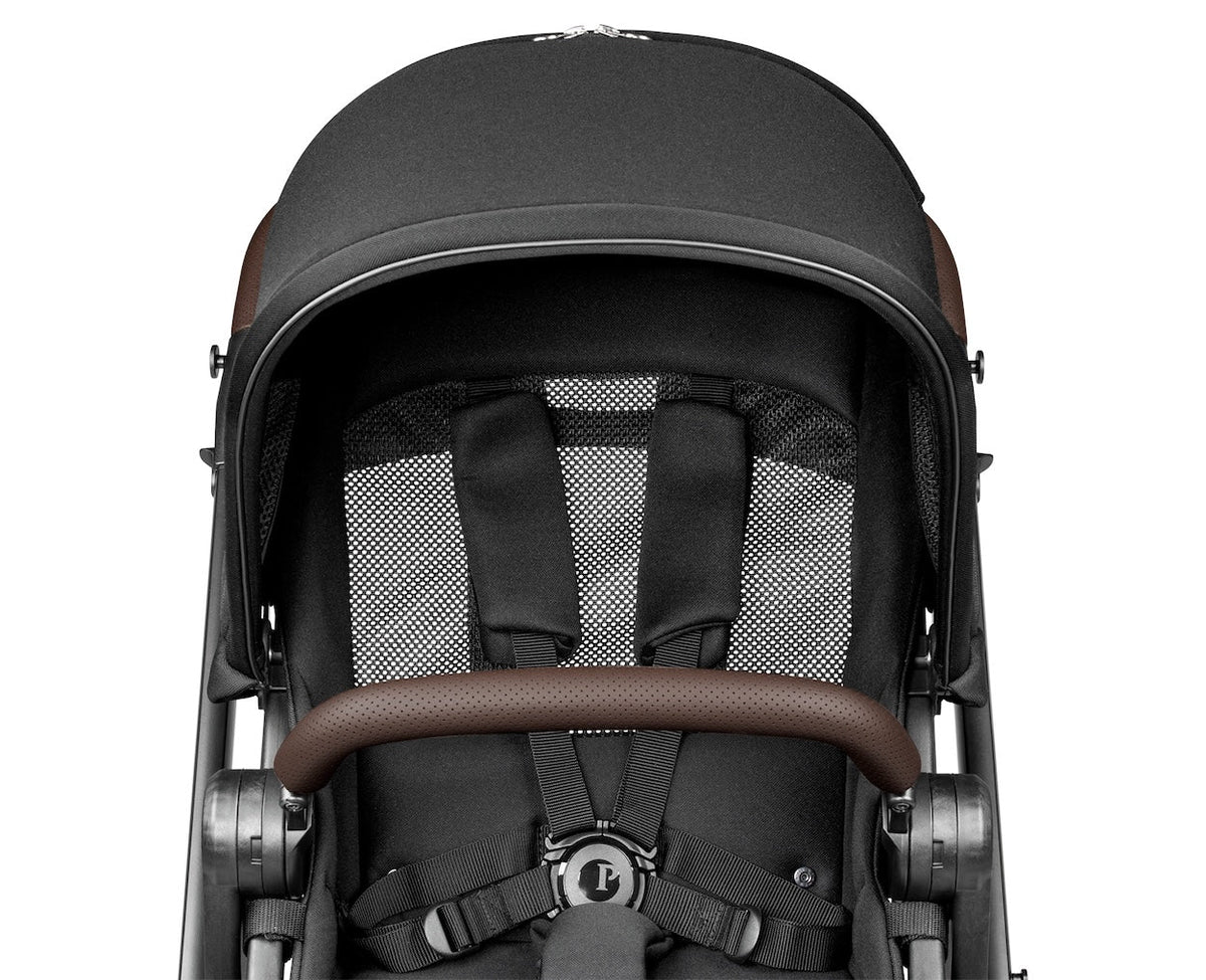 Close-up of a baby stroller with a black canopy and brown accents on a white background
