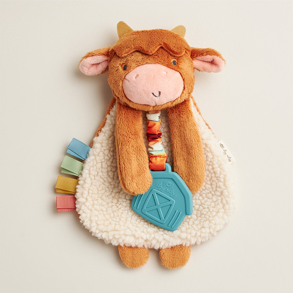 Plush cow toy with colorful elements on a light background