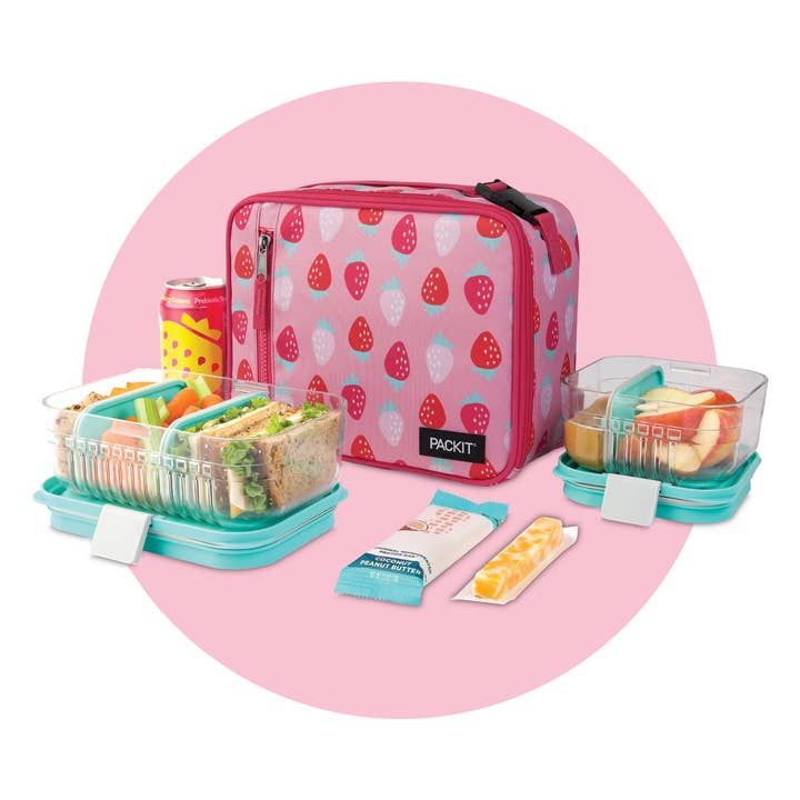 Pink lunch bag with strawberry pattern and contents on a pink background