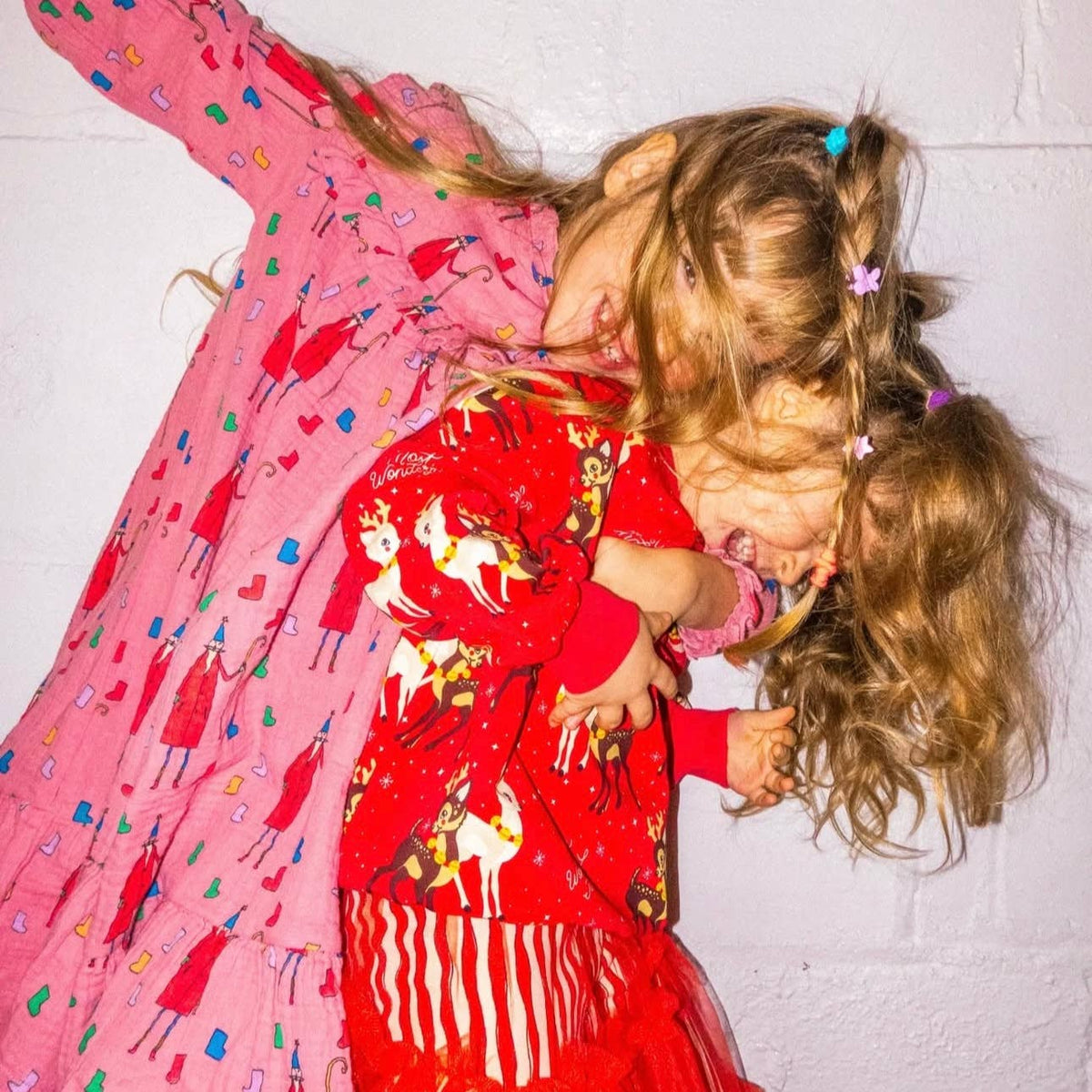 Two children in colorful pajamas lying on a white floor.