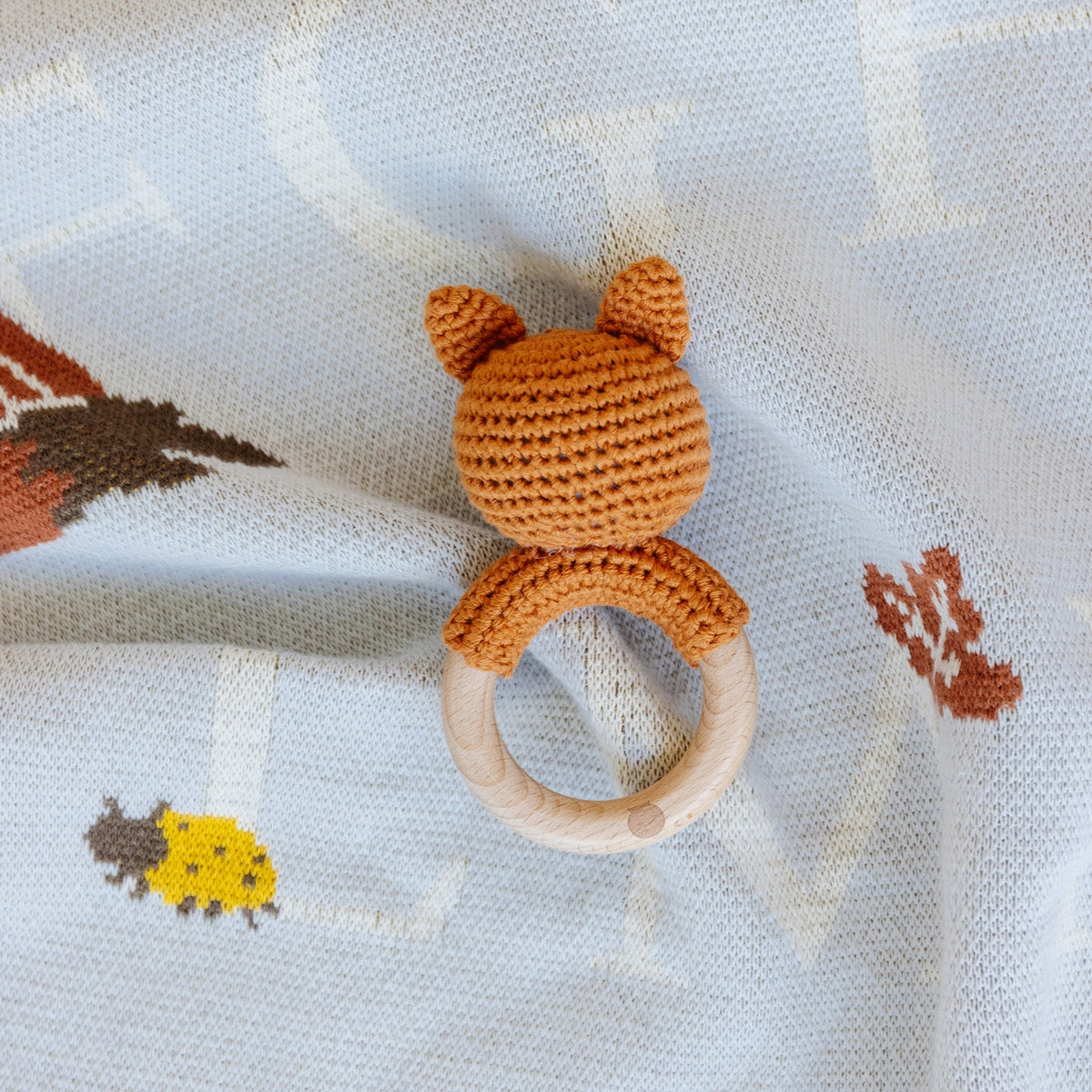 Crocheted fox-shaped teething ring on a soft fabric background