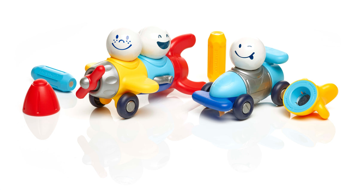 A set of colorful wooden toy cars and accessories on a white reflective background. The set includes two small wooden cars with smiling tooth-shaped driver heads, one yellow car with a red propeller and one blue car with a yellow propeller, plus separate pieces in blue, red, yellow, and gray.