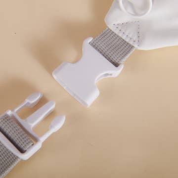 Close-up of a white plastic buckle with metal webbing on a beige background