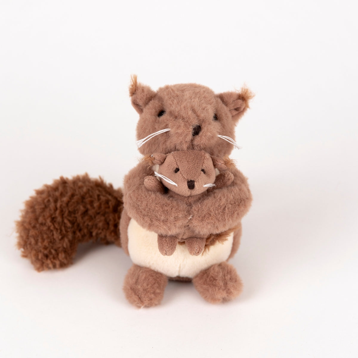 Stuffed animal squirrel holding a baby squirrel on a white background