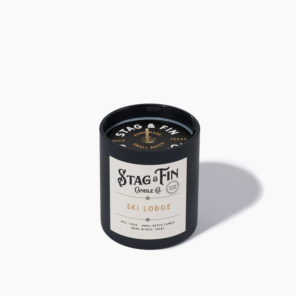 Stag & Fin candle with black lid and white label on a light gray background