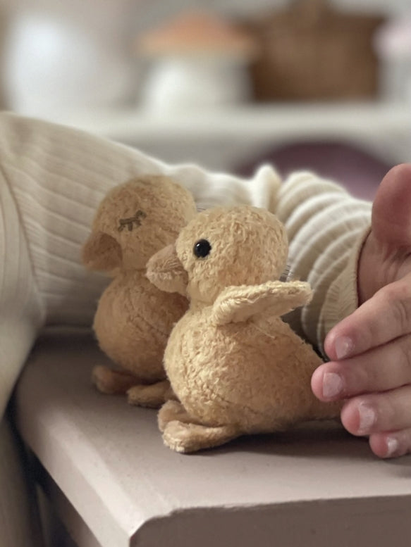 Two small plush mice on a surface with a blurred background