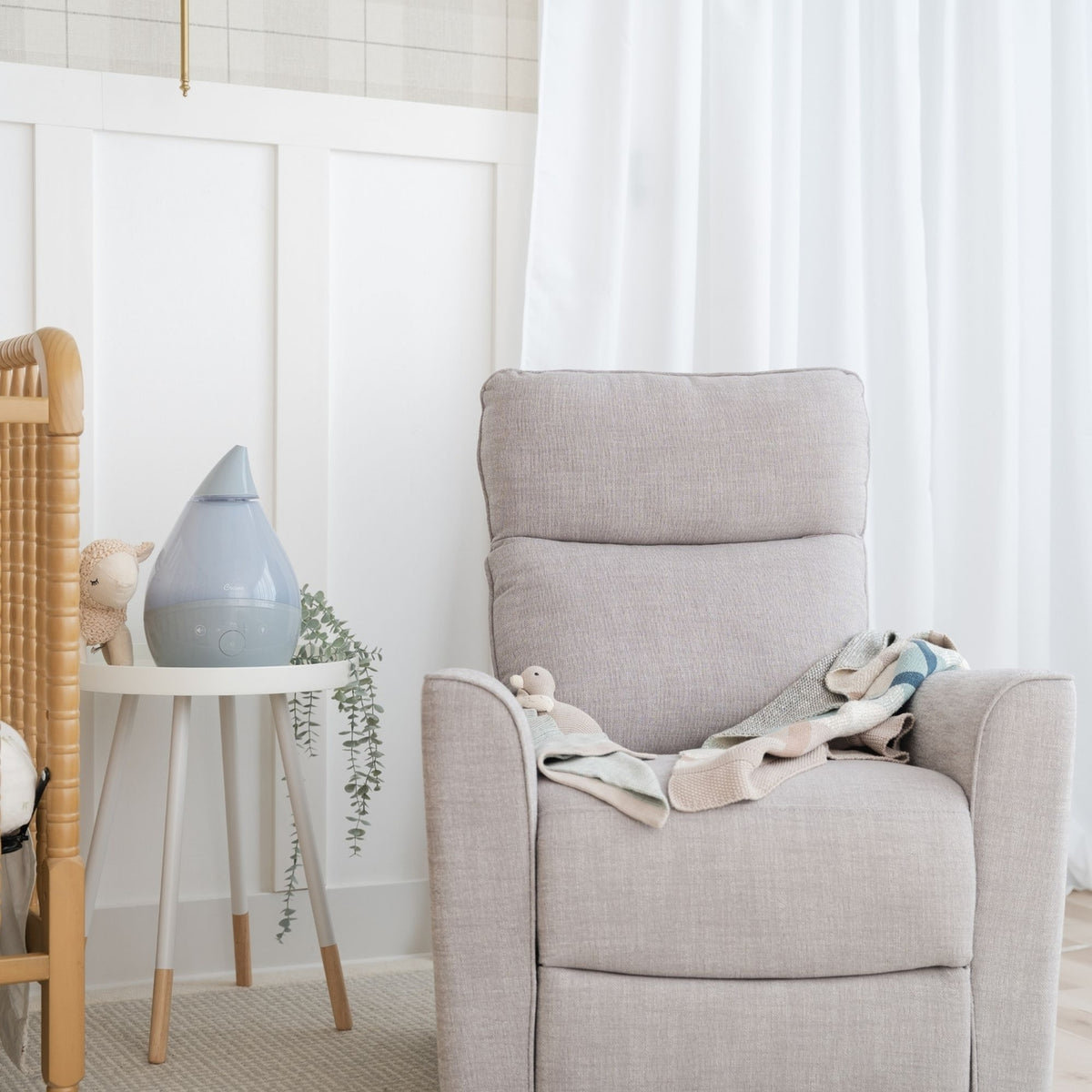 Gray armchair with a blanket in a room with white walls and a small table.