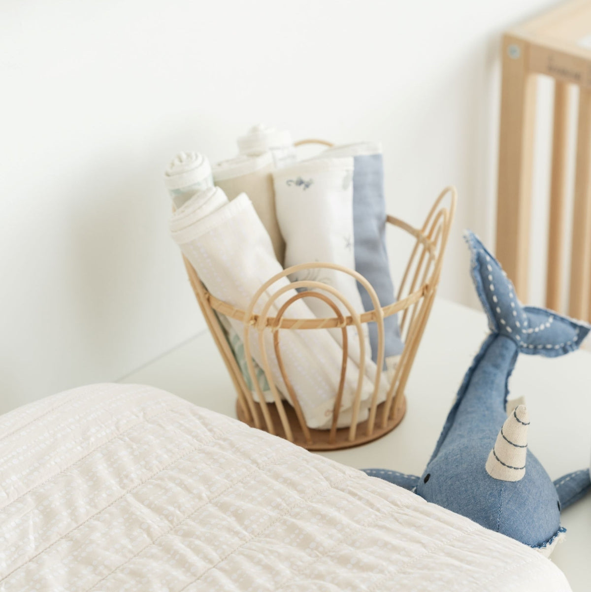 Basket with baby items and a blue plush toy on a white surface