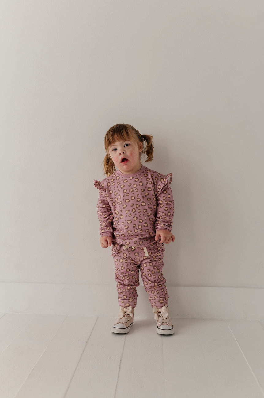 Child wearing a pink outfit with ruffled sleeves against a white background