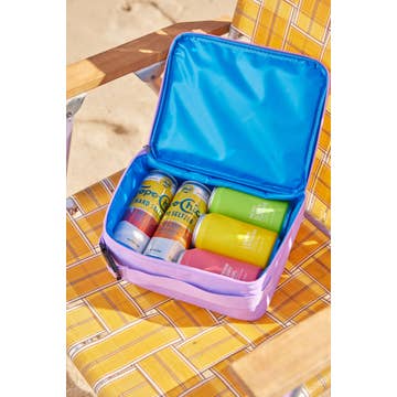 Colorful drinks in a purple cooler on a yellow checkered tablecloth